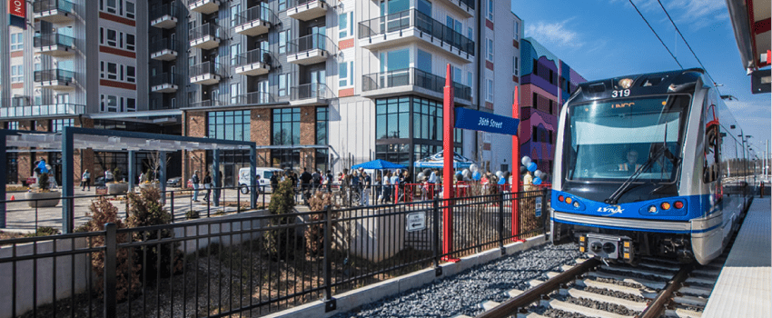 The Light Rail pulling up to a stop outside of an apartment building in NoDa.