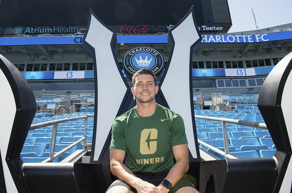 Bronico posing in the Charlotte FC fan throne in Charlotte 49er gear