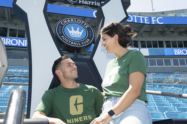 Bronicos smiling at each other with sitting on the Charlotte FC fan throne